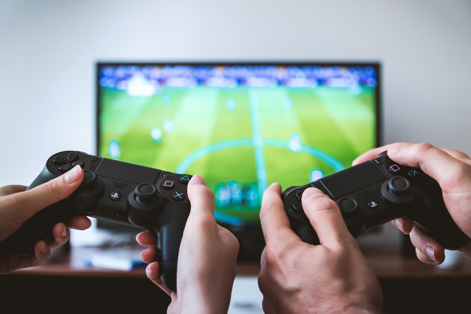 Twee personen spelen voetbalgame op console.