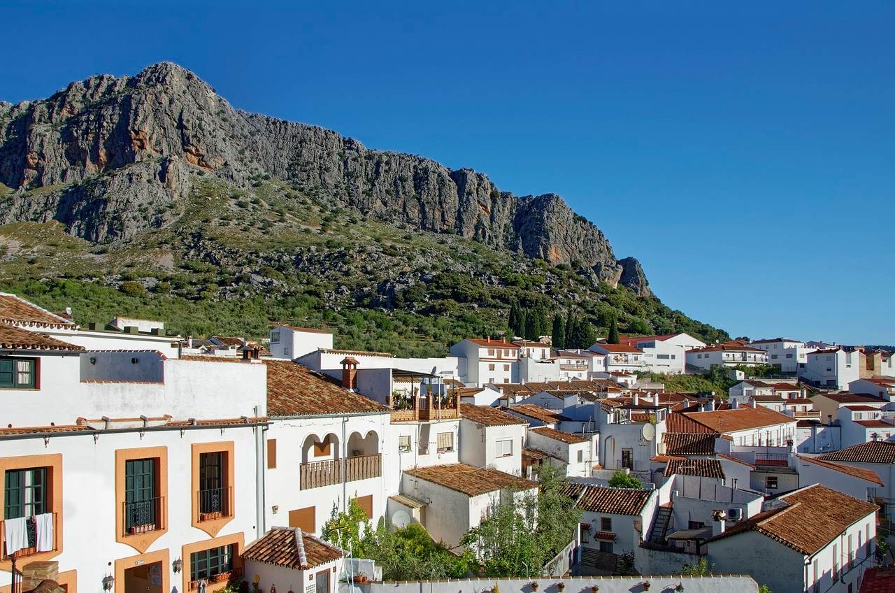 zonnig sfeerbeeld van witte klassieke woningen in spanje met gebergte op achtergrond