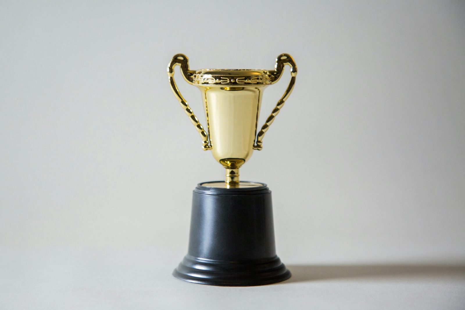 Gouden trofee op zwarte sokkel tegen witte achtergrond
