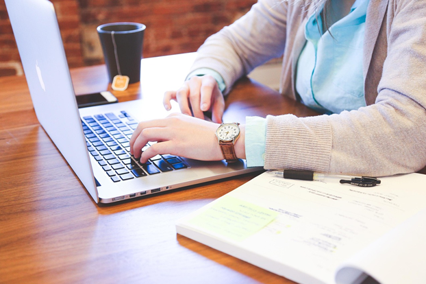 Persoon typt op laptop aan houten bureau